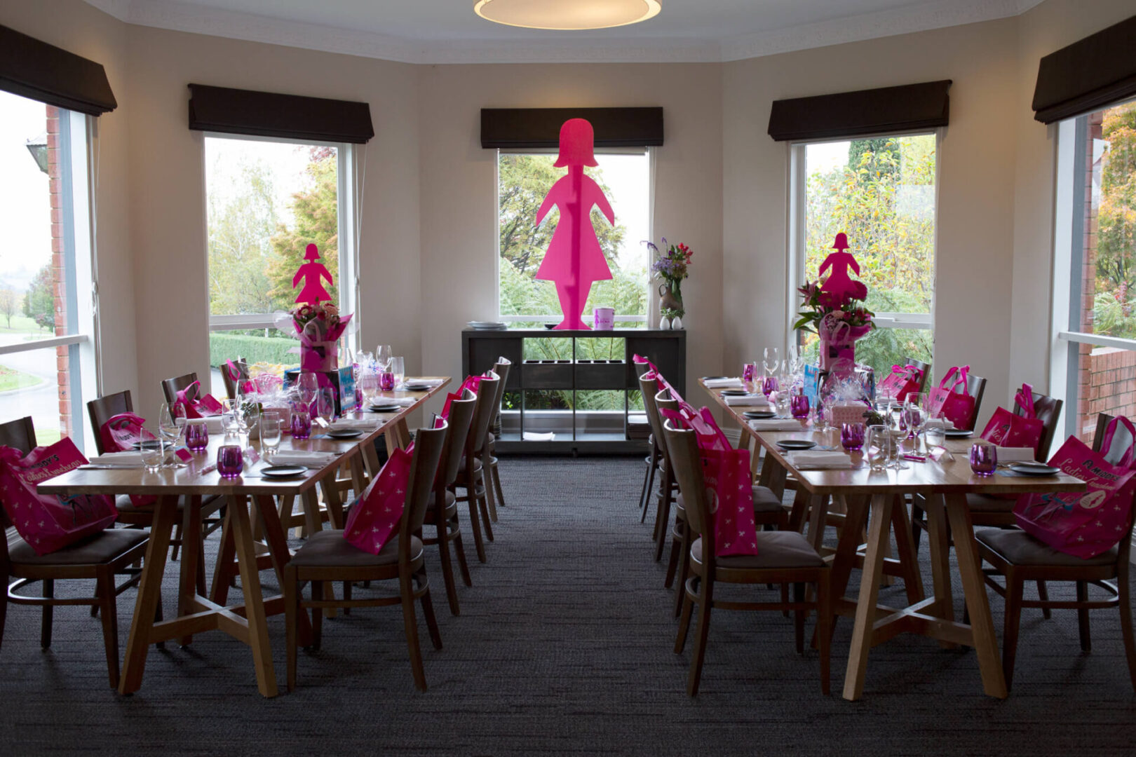 A room filled with tables and chairs covered in pink cloth.