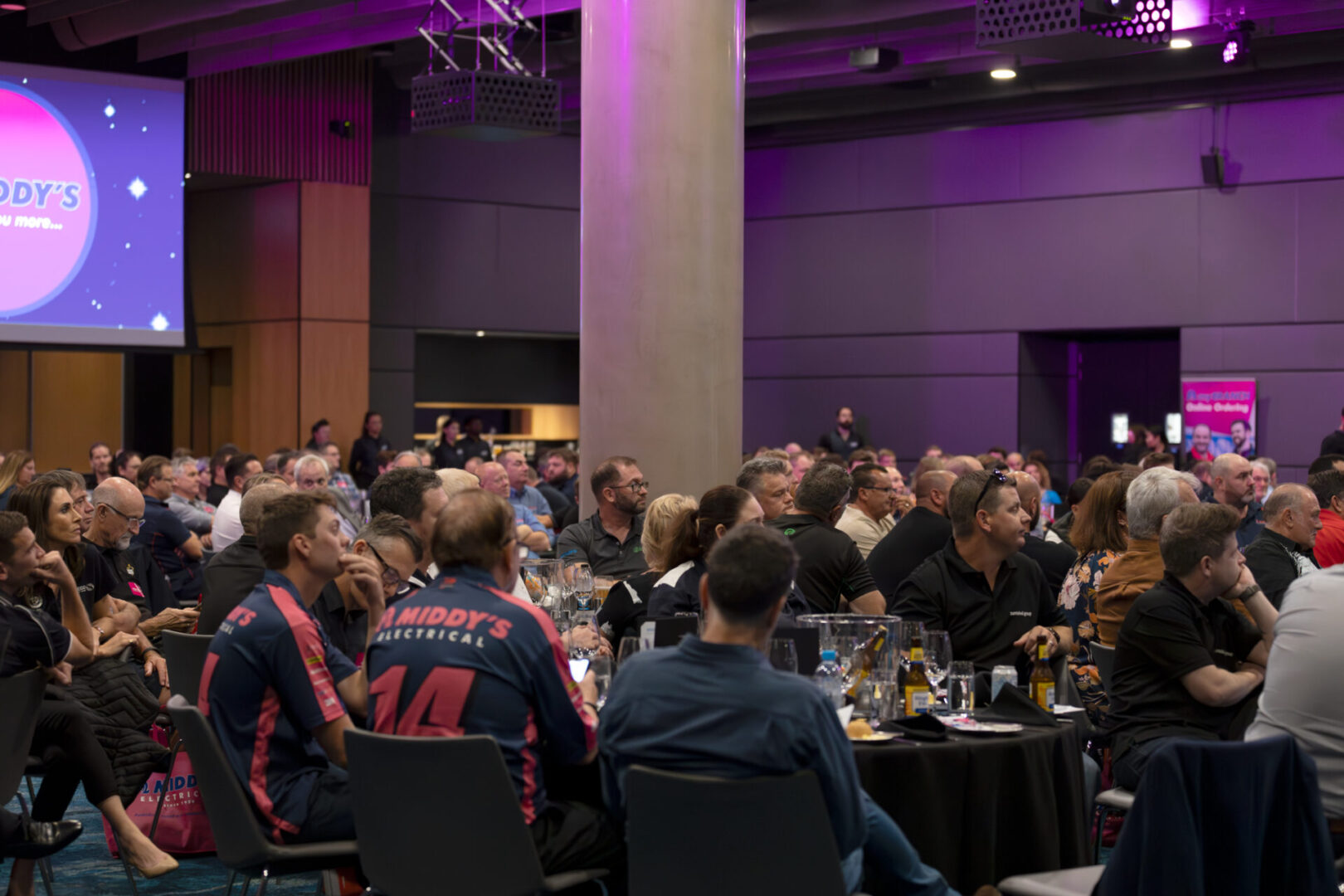 A group of people sitting at tables with wine glasses.