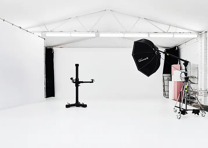 A photo studio with a white backdrop and black stand.