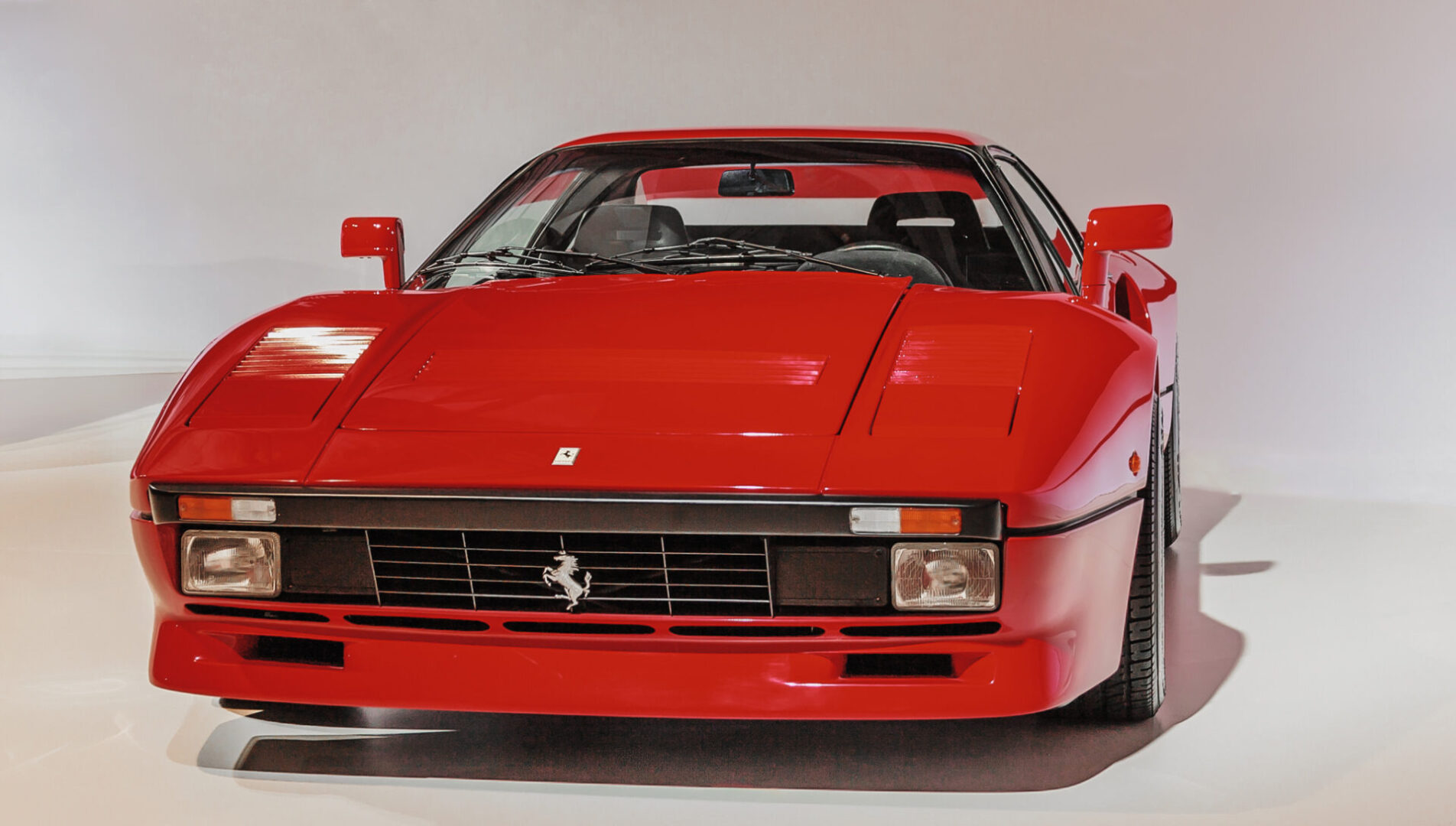 A red ferrari car is parked on the floor.